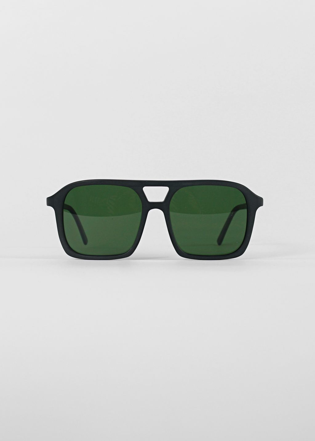 Black sunglasses with green lenses on a light gray background