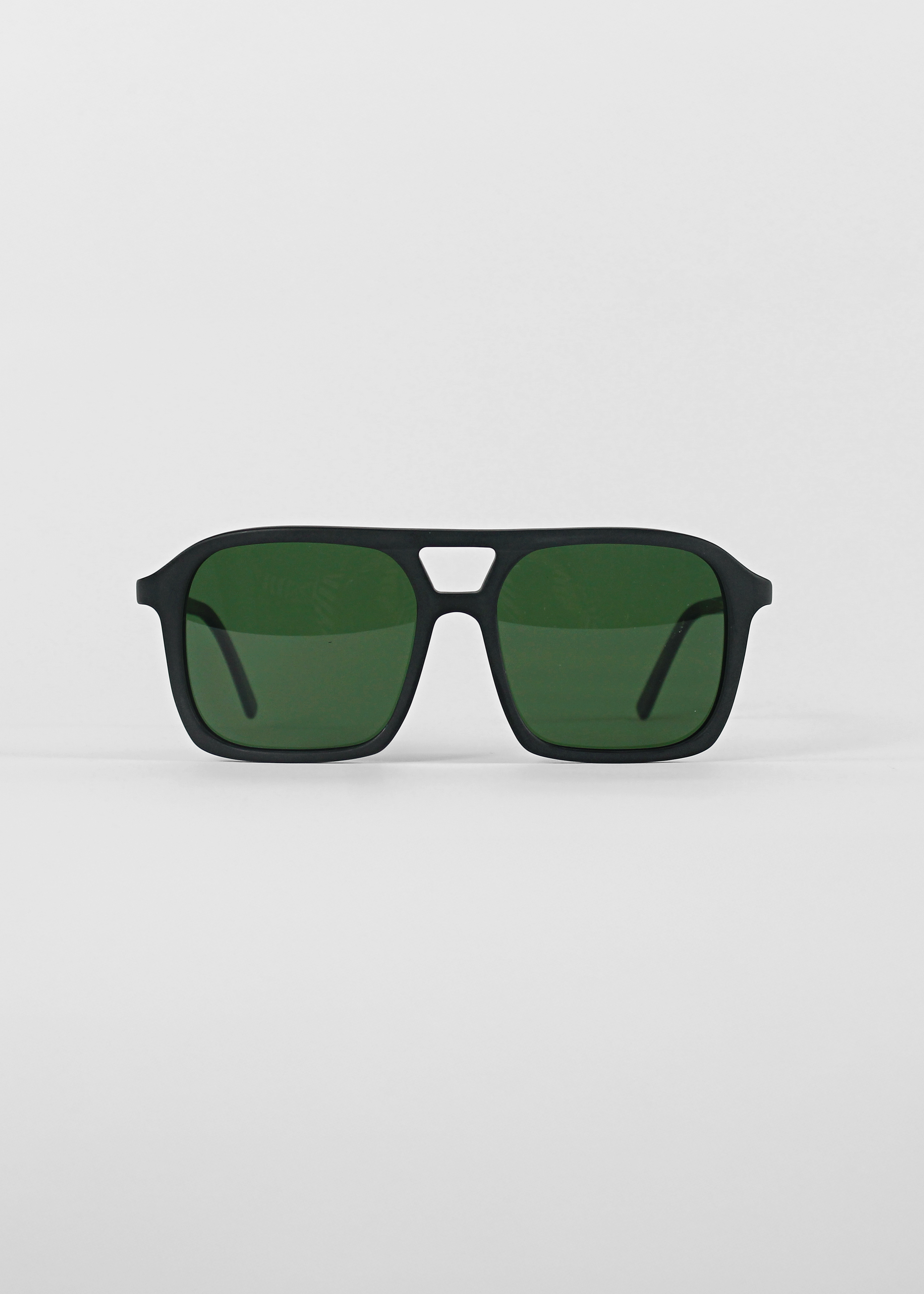Black sunglasses with green lenses on a light gray background